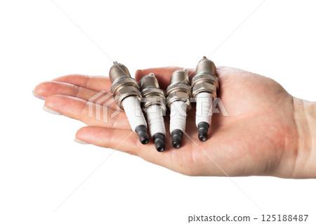 Car spark plugs in a girl's hand on a white background, isolate. Close-up 125188487