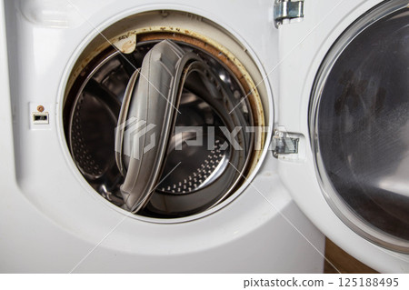 An old torn rubber seal for the sunroof with a defect, in the washing machine. Replacement of faulty spare parts, industry 125188495