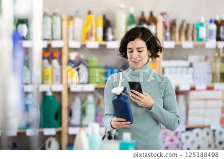 Adult woman scanning qr code for cleaning spray Adult woman scanning qr code for cleaning spray 125188498