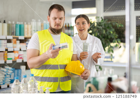 male builder chooses an ointment in a pharmacy 125188749