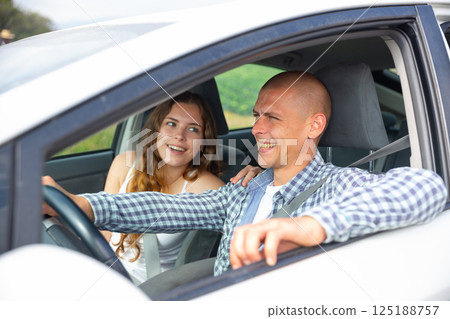 Cheerful man driving car with girlfriend in passenger seat 125188757