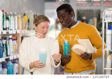During shopping, African male client with wife advised and choose shampoo, shower gel, bast wisp 125188797