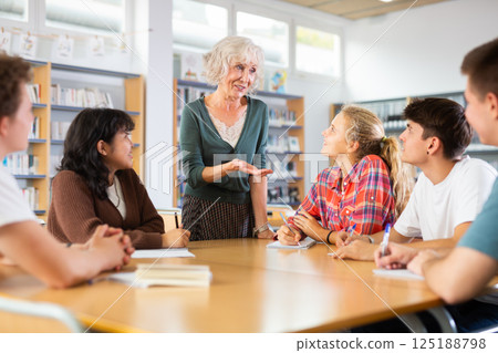Portrait of adult female librarian and diligent schoolkids during classes in library Portrait of adult female librarian and diligent schoolkids during classes in library 125188798