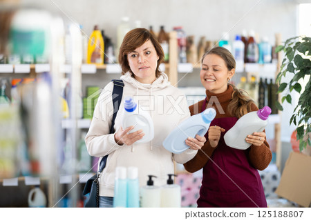 Girl consultant helps woman buyer choose liquid detergent 125188807