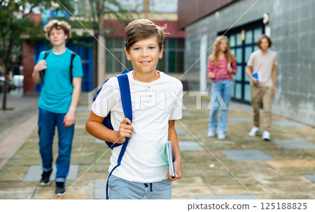 Teen boy walk along summer street after finishing college lessons 125188825