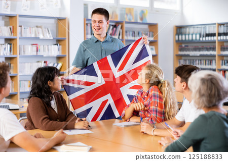 School student boy tells her classmates about the country of Great Britain, holding flag in her hands School student boy tells her classmates about the country of Great Britain, holding flag in her hands 125188833