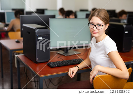 Clever female teenager wearing glasses and solving tasks of computer science in the auditory Clever female teenager wearing glasses and solving tasks of computer science in the auditory 125188862
