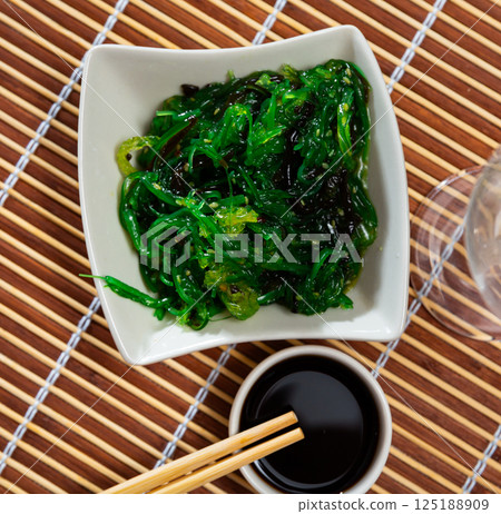 Chuka seaweed with sesame seeds in white bowl and wooden sticks 125188909