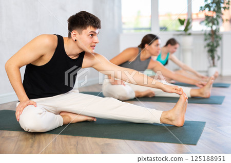 Young guy stretches and prepares to perform Jana Shirshasana Young guy stretches and prepares to perform Jana Shirshasana 125188951