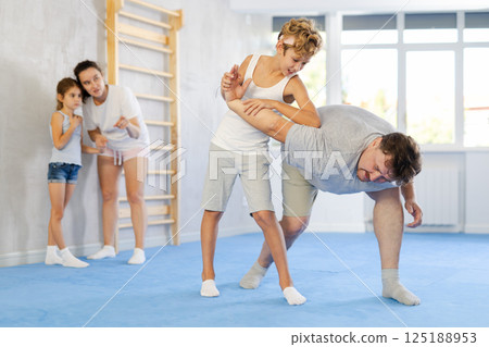 Father teaches his son to use forceful techniques and grips during self defense classes 125188953
