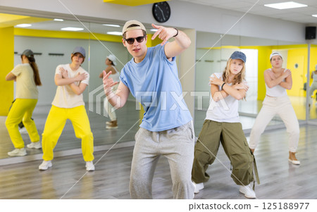 Group of young confident teenagers in casual clothes dancing together during exercise in class 125188977