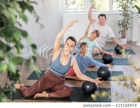 Family with two kids doing pilates with softball 125188978