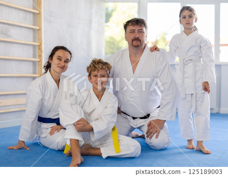 Friendly sporty family with tween children in kimonos posing in gym 125189003