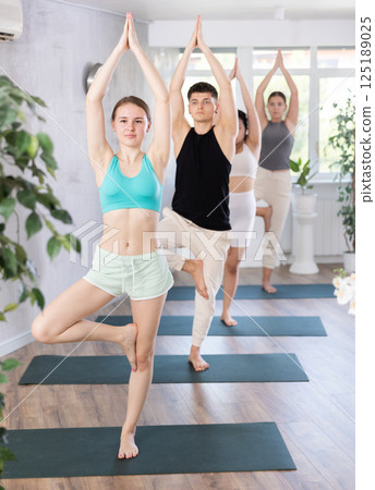 Fitness, sport and healthy lifestyle concept: woman doing yoga yoga pose - vrikshasana pose on mat 125189025
