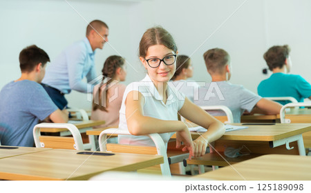 Cheerful teen girl in glasses studying in classroom 125189098
