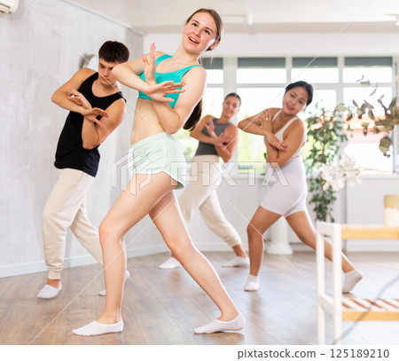 Girl teen perform choreographic exercise and teach energetic mobile social dance groove with friends Girl teen perform choreographic exercise and teach energetic mobile social dance groove with friends 125189210