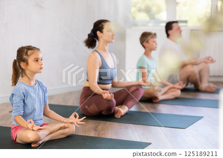 Family with two children doing yoga in studio 125189211