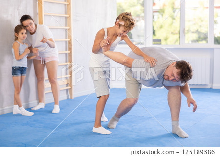 Father teaches his son to use forceful techniques and grips during self defense classes 125189386