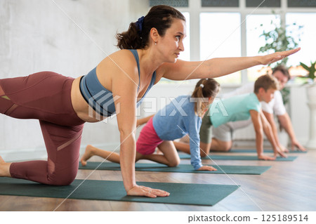 Confident mom, dad, son and daughter perform bird dog power asana 125189514