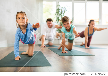 Confident mom, dad, son and daughter perform bird dog power asana Confident mom, dad, son and daughter perform bird dog power asana 125189527