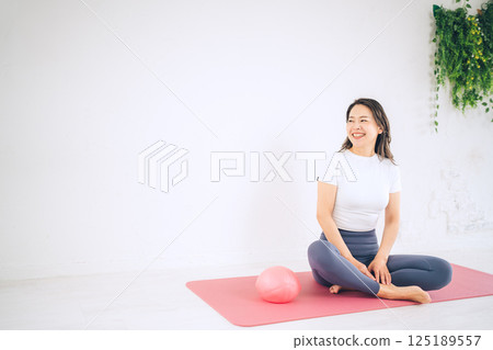 坐在瑜珈墊上的中年婦女 坐在瑜珈墊上的中年婦女 125189557