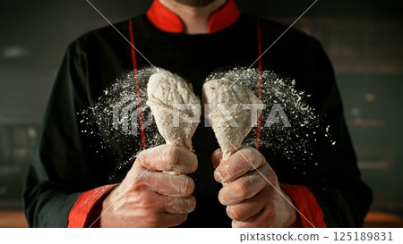 Freeze Motion of Hitting Raw Chicken Legs Covered with Flour . Closeup of Meat Preparation 125189831