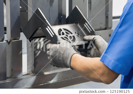 Close up the bending machine operator hold the sheet metal parts with rubber glove. 125190125