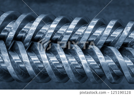 Close up scene body of the barrel screw of injection machine spare parts in the light blue scene. Close up scene body of the barrel screw of injection machine spare parts in the light blue scene. 125190128