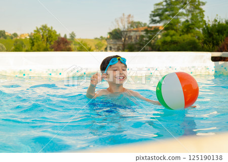 Happy child playing with colorful inflatable ball in swimming pool 125190138