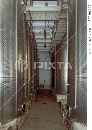 Rows of stainless steel tanks filling a wine cellar Rows of stainless steel tanks filling a wine cellar 125190142