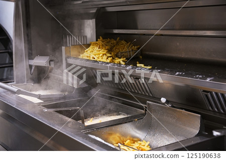 Commercial Fry Station with Steaming Freshly Cooked Fries 125190638