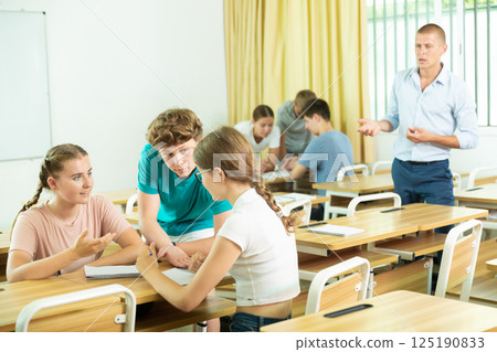 Classmates and teacher working in groups to complete task during class 125190833