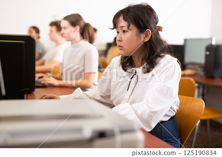 Portrait of diligent asian college girl studying in computer room using computer 125190834
