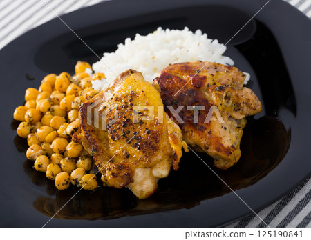 Tasty chicken thighs with cheakpea and rice at plate 125190841