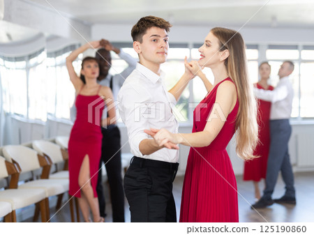 Hispanic guy practicing samba with woman in red in dance class 125190860