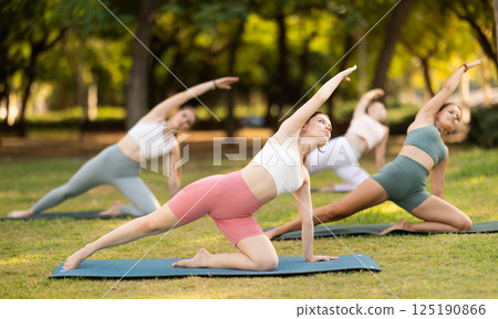 Yoga lesson visitors girls perform Parighasana in park Yoga lesson visitors girls perform Parighasana in park 125190866