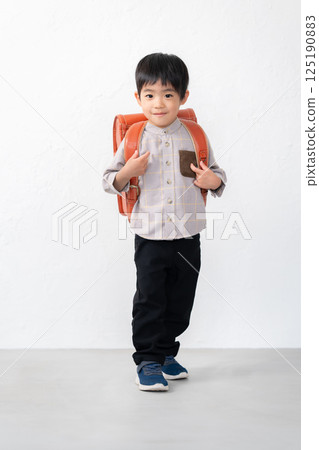 5-year-old boy carrying a school bag 125190883