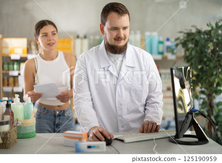 Male pharmacist helps female customer find prescription medication 125190959
