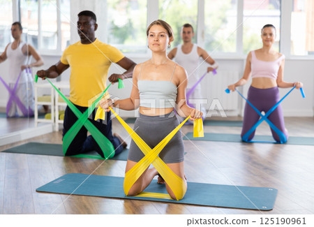 Group of women and men with working out with rubber bands on my knees Group of women and men with working out with rubber bands on my knees 125190961