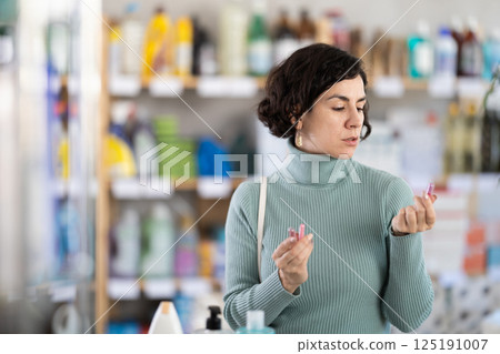 Adult woman chooses lipstick sample in store Adult woman chooses lipstick sample in store 125191007