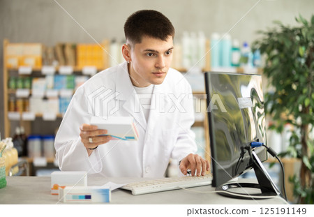 Young pharmacist holding boxes of pills Young pharmacist holding boxes of pills 125191149