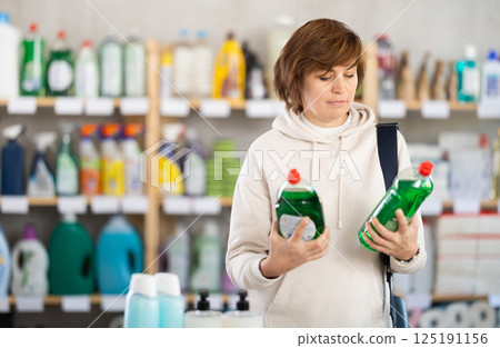 Adult woman chooses dishwashing detergent in store Adult woman chooses dishwashing detergent in store 125191156