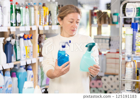 Adult woman chooses cleaning spray in store 125191183
