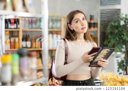 Young girl is scanning QR on a package of Juaozi in grocery store Young girl is scanning QR on a package of Juaozi in grocery store 125191184