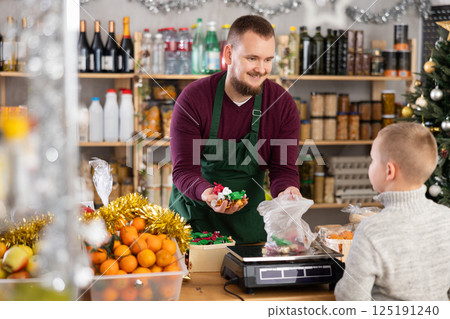 Salesman weighs candies in a supermarket 125191240