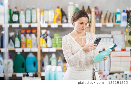 Young woman scanning qr code for cleaning spray 125191253