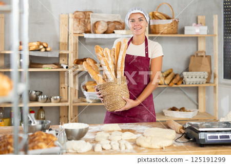 Young woman are standing in kitchen with basket of finished products baguettes 125191299