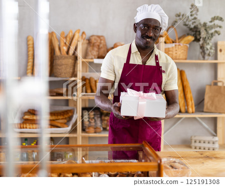 Portrait of male baker with cake box in hands in bakery interior 125191308