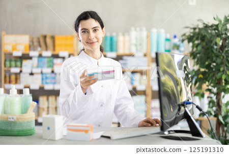 Woman pharmacist looking for pills on computer Woman pharmacist looking for pills on computer 125191310
