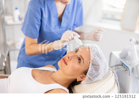 Young woman receiving cosmetic facial radiofrequency facial procedure Young woman receiving cosmetic facial radiofrequency facial procedure 125191312